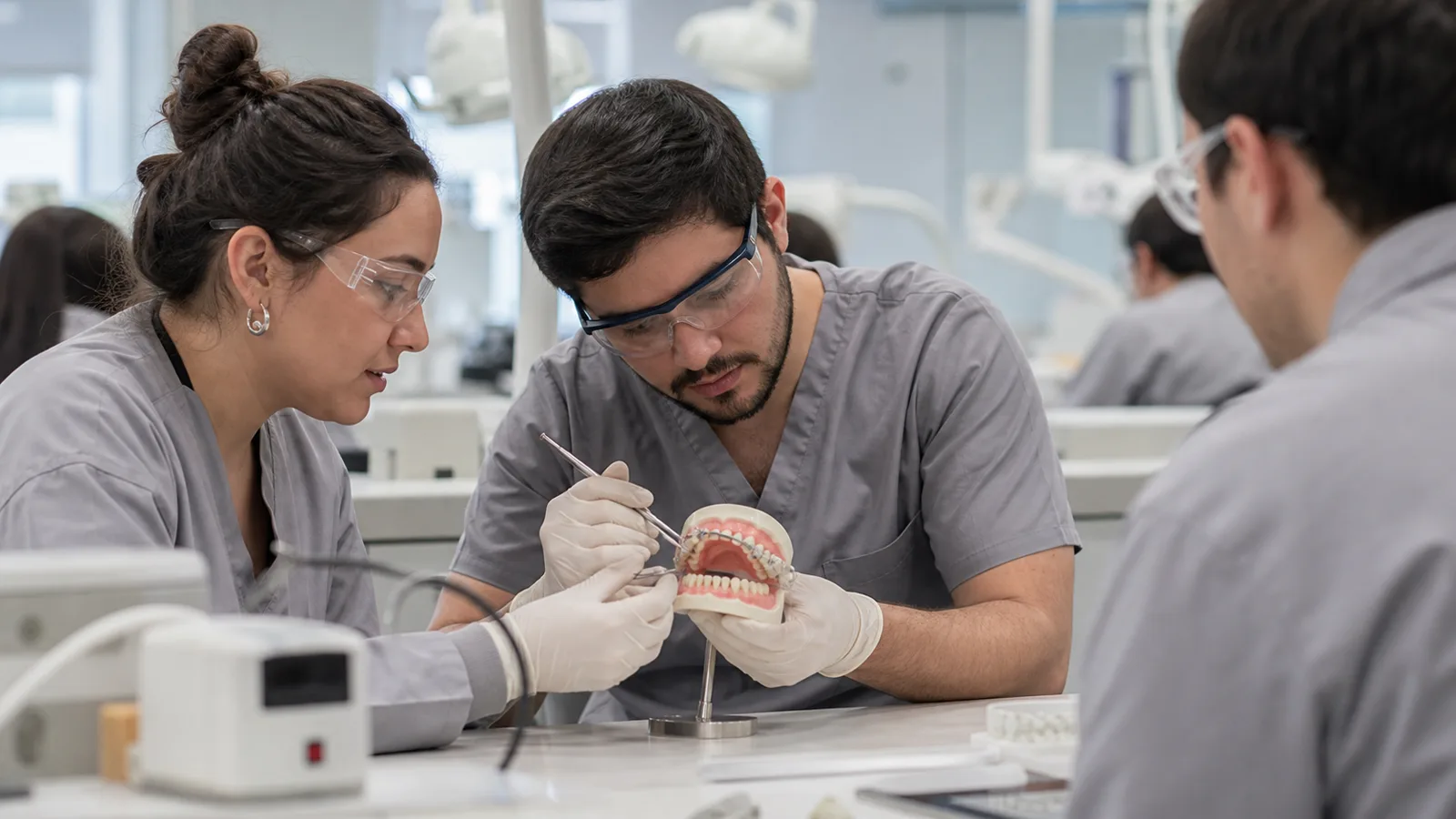 Estudiantes de Odontologia ajustando un aparato de ortodoncia en un modelo